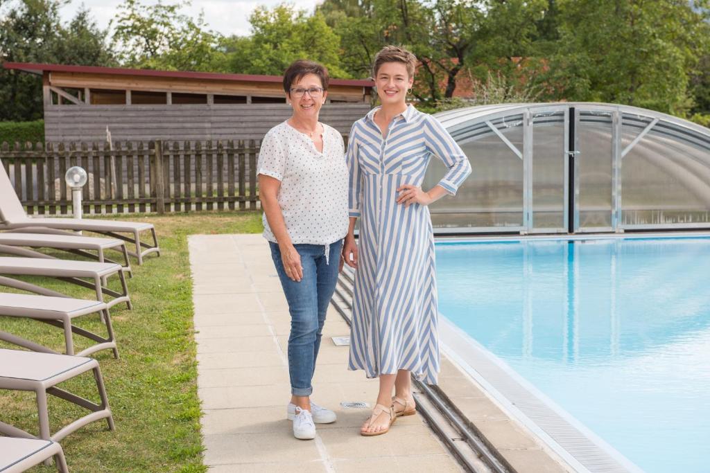 two women standing next to a swimming pool at Pension Cäcilia in Pöllau