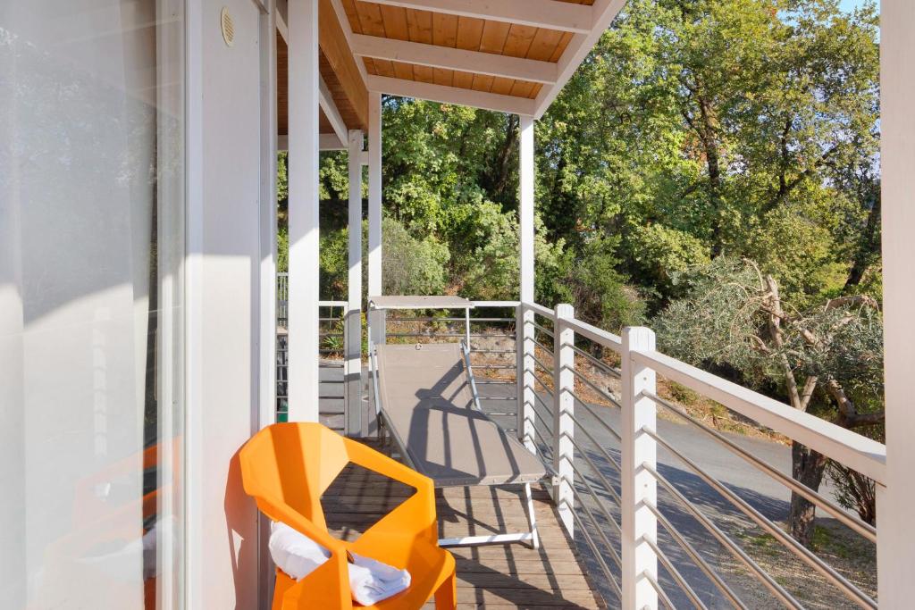 uma cadeira laranja sentada no alpendre de uma casa em Mobile Home Next 232 em Pietra Ligure