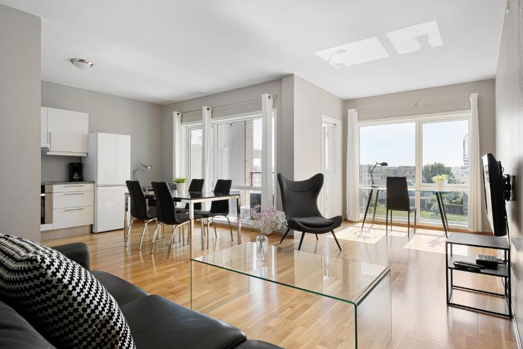 een woonkamer met een glazen tafel en stoelen bij Frogner House - Forus Leilighetshotell in Stavanger