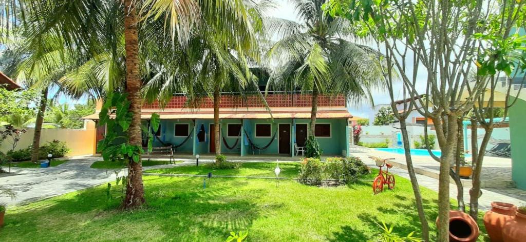 a house with palm trees in front of it at Pousada Anauê - Conde in Jacumã