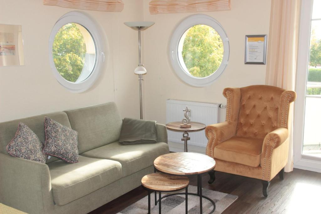 a living room with a couch and a chair and two windows at StrandGut in Boltenhagen