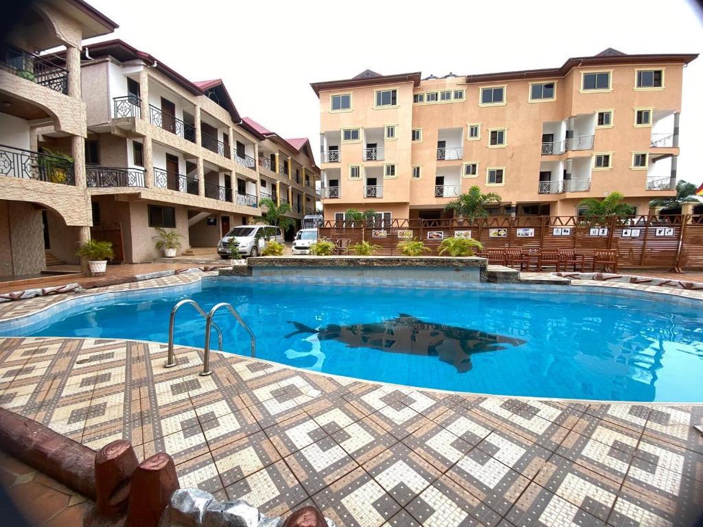 ein Pool vor einigen Apartmentgebäuden in der Unterkunft Lou Ralph Hotel in Accra