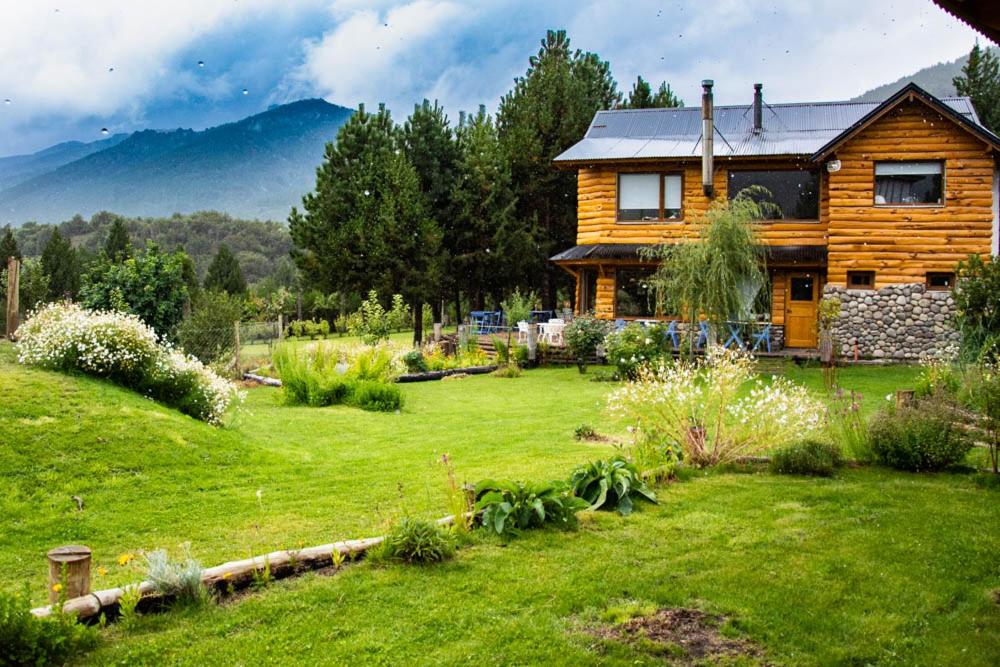 a wooden house in a field of green grass at Cinco Sentidos Hosteria in Villa Meliquina