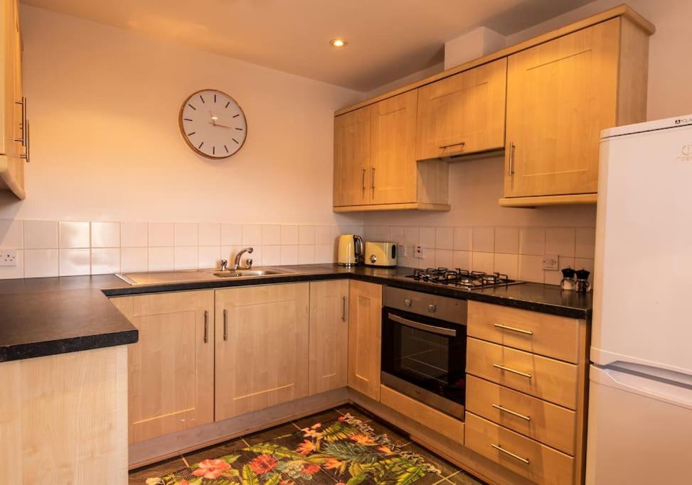 a kitchen with wooden cabinets and a clock on the wall at Belfast Apartment in Belfast