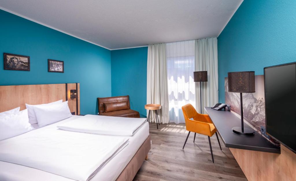 ミュンヘンにあるメルキュール ホテル ミュンヘン ノイパーラッハ ズートのベッドとデスクが備わるホテルルームです。