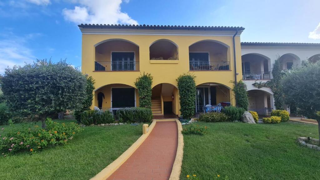 ein gelbes Haus mit einem roten Backsteinweg davor in der Unterkunft Casa Il Pescatore in Porto Pozzo