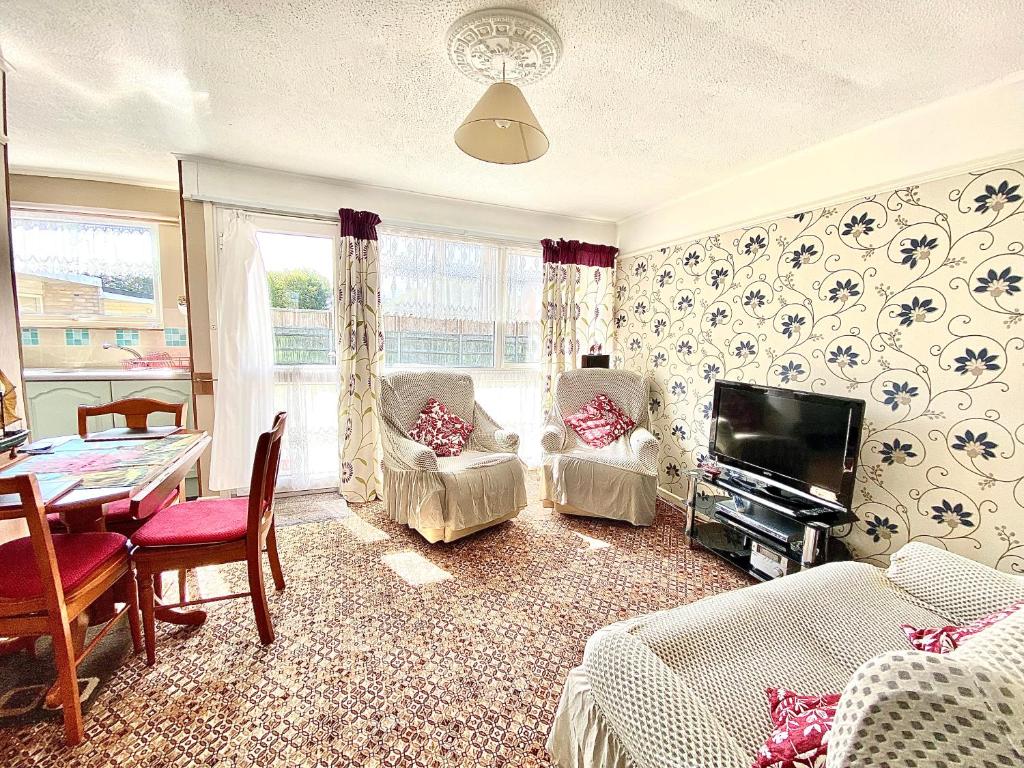 a living room with a television and a table and chairs at Quiet and Comfy 2- bedroom Holiday Chalet, walk to the beach, Norfolk in Great Yarmouth