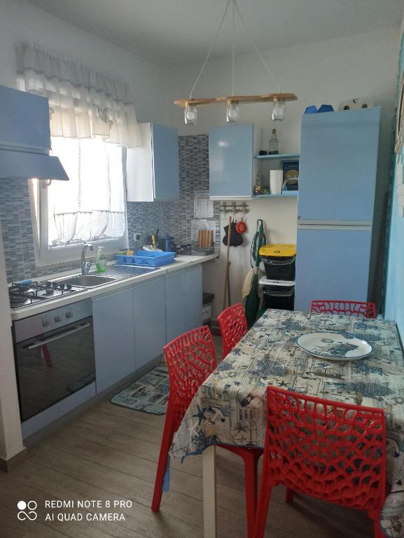 una cucina con tavolo con sedie rosse e una cucina con lavandino di Rosa dei Venti house a Campomarino
