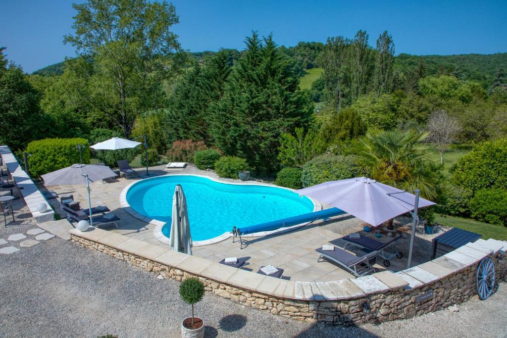 an outdoor swimming pool with umbrellas and chairs at Domaine des Pierres Blanches - Gite La Salamandre in Carlux