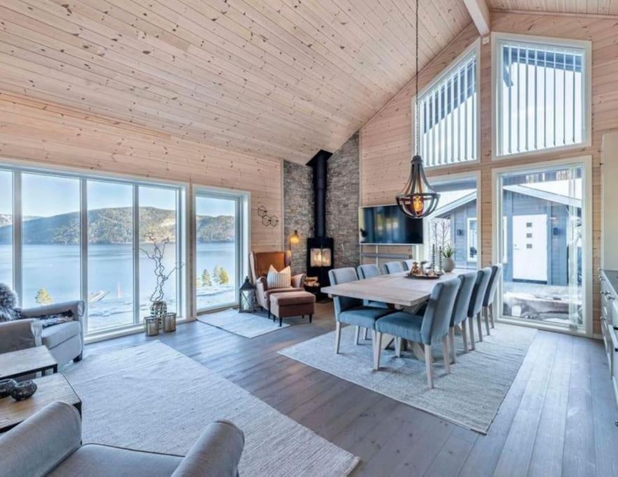 un comedor con mesa y sillas y una habitación con ventanas en Modern cabin with panoramic view of the Nisser See, 