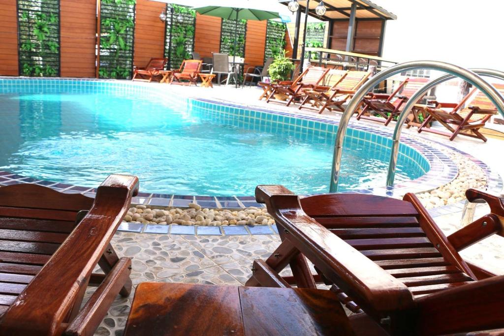 uma piscina com duas cadeiras e uma mesa e um ecrã em Mali Namphu Hotel em Vientiane