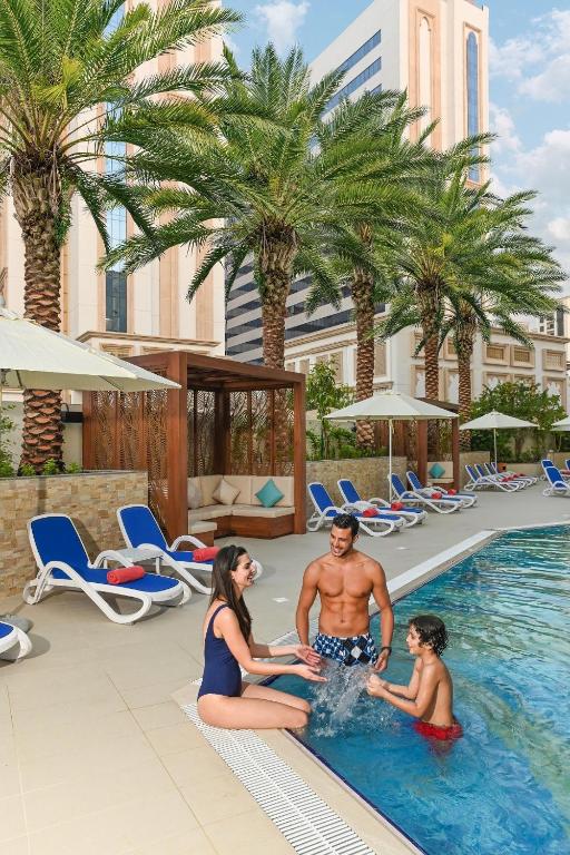 ドバイにあるArabian Park Dubai, an Edge by Rotana Hotelのリゾートのプールに座っている人々のグループ