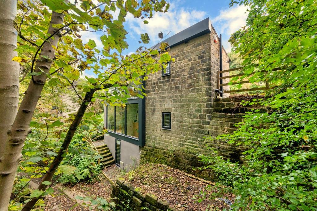a brick building with a blue door and stairs at Finest Retreats - Luxurious Hidden Cragg Vale Escape by Hebden Beck in Hebden Bridge