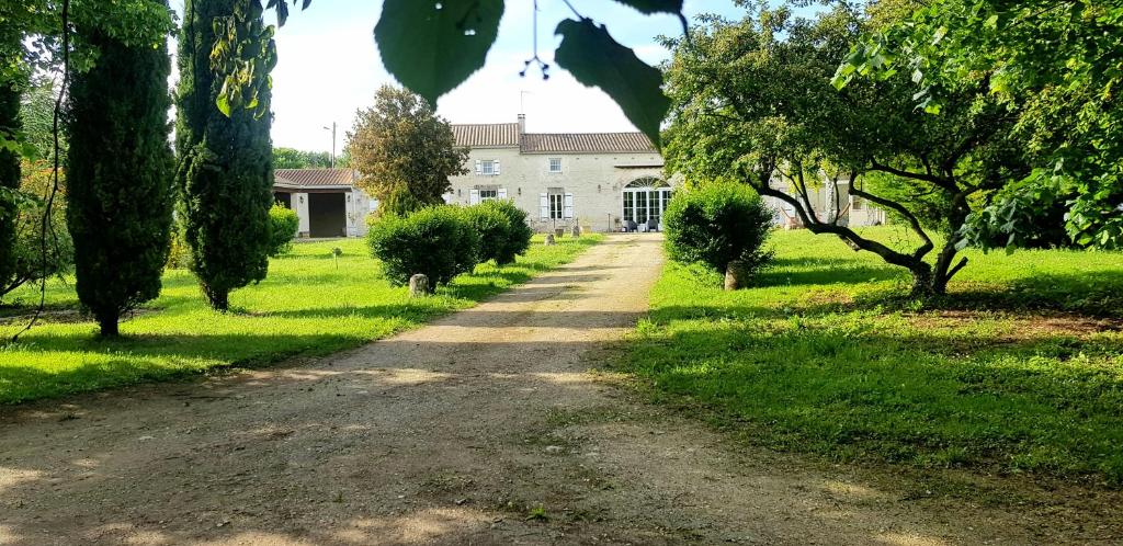 un camino de tierra frente a una casa con árboles en La Revêtizon, en Siecq