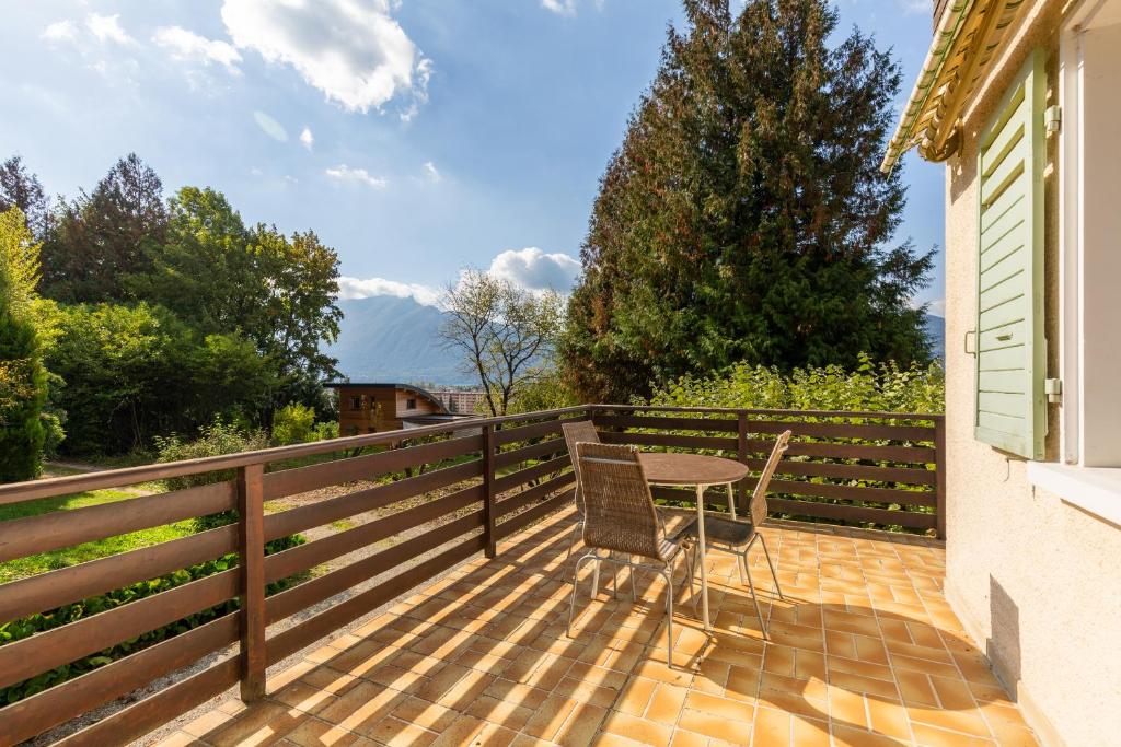 een patio met een tafel en stoelen aan een hek bij Chalet Les Tourelles in Aix-les-Bains