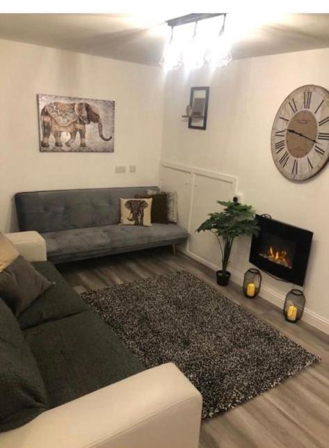 ein Wohnzimmer mit einem Sofa und einer Uhr an der Wand in der Unterkunft Lovely ground floor apartment with easy parking. in Belfast