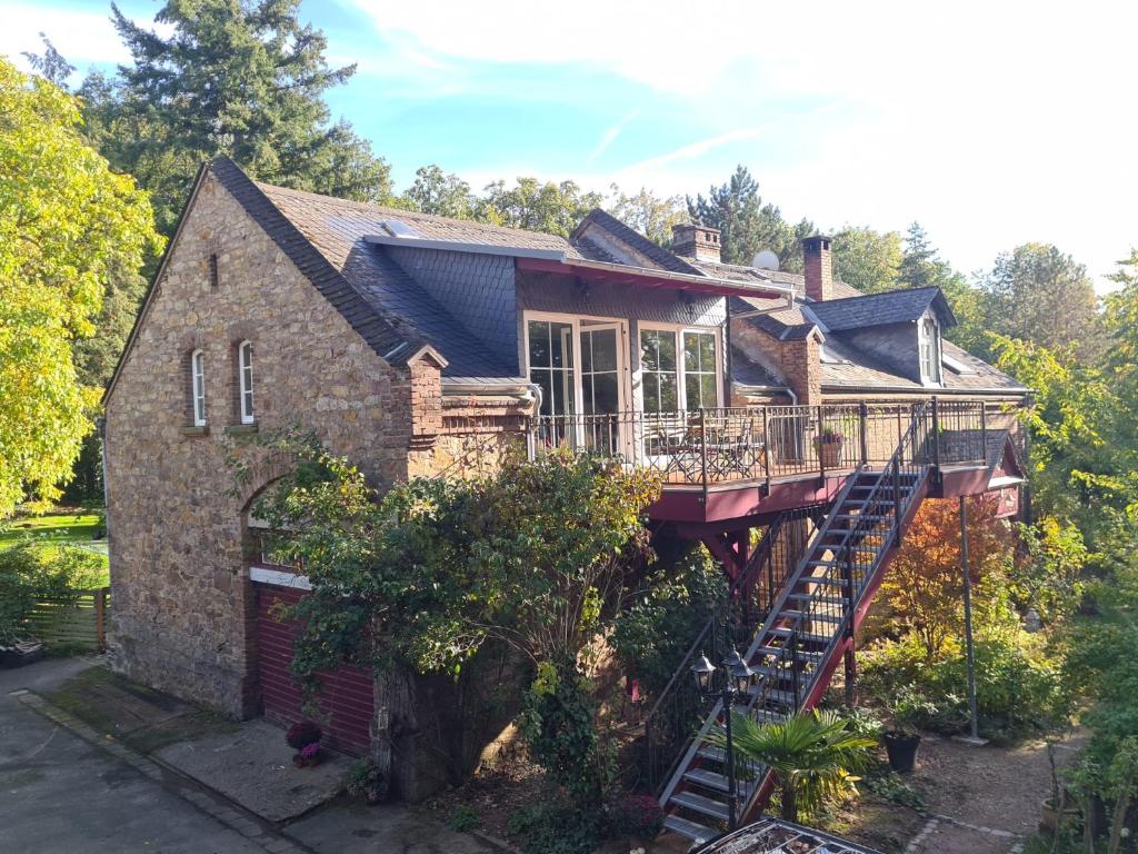 an old brick house with a deck and a staircase at Neue Ferienwohnung im alten Forsthaus in Rüdesheim am Rhein