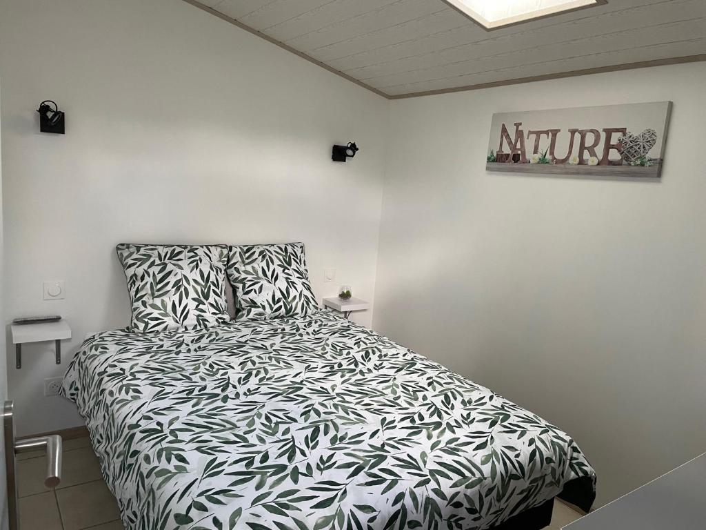 1 dormitorio con 1 cama con edredón blanco y negro en Gîte Le petit quartier en Berson