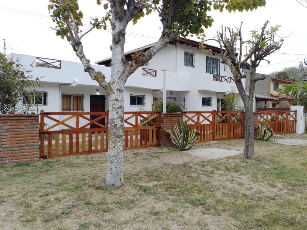 una casa con una valla de madera y dos árboles en Alojamientos frente al Mar Complejo "El Estar De La Costa" en San Clemente del Tuyú