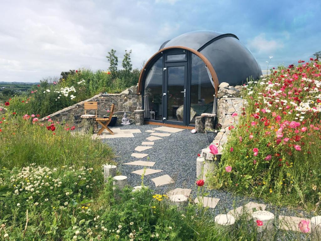 a building with a dome in a field of flowers at Hilltop Hideaway - Secluded pod with private hot tub in Newry
