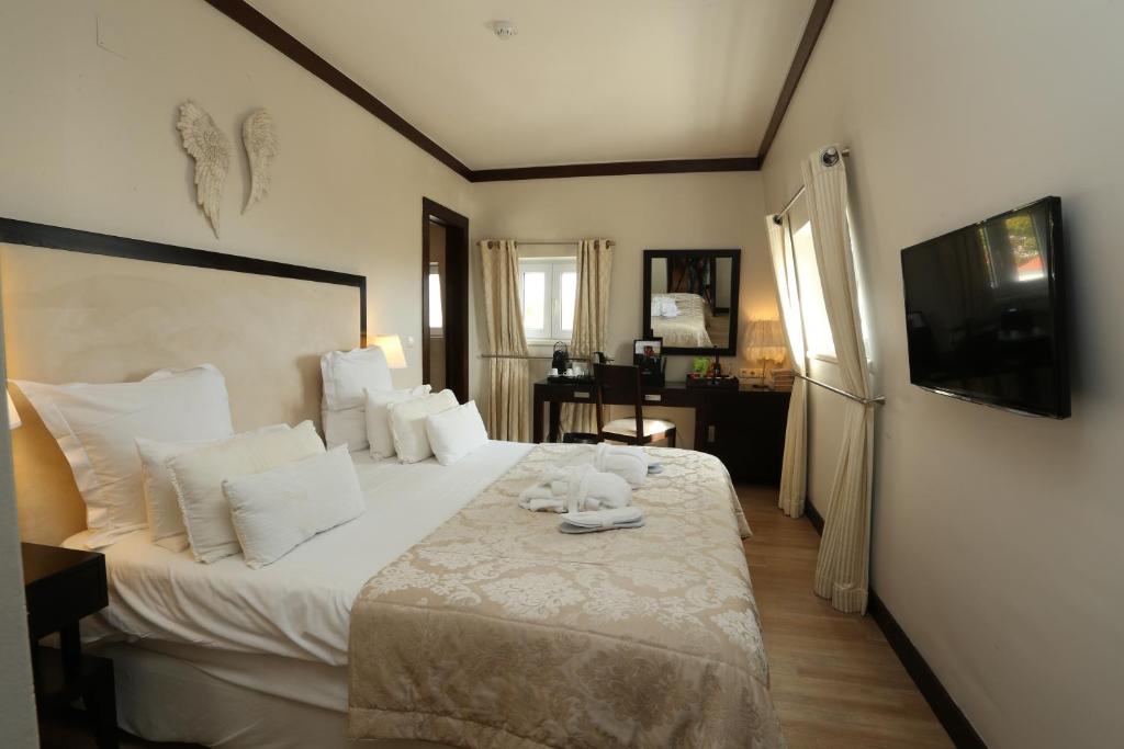 a bedroom with a large bed with white pillows at Hotel Inglaterra - Charme & Boutique in Estoril