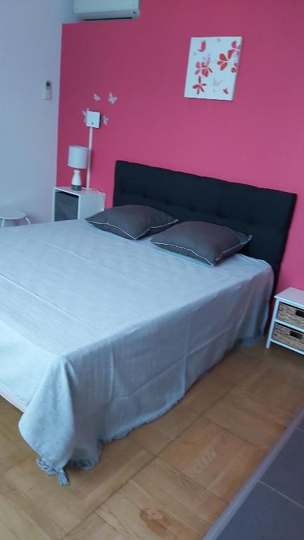 Saint-Jean-Pla-de-CortsにあるMaison MICDENのピンクの壁のベッドルーム1室(大型ベッド1台付)