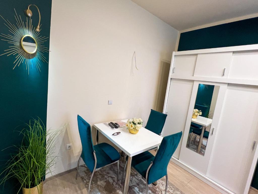 a dining room with a white table and blue chairs at Dis apartman 2 in Kruševac