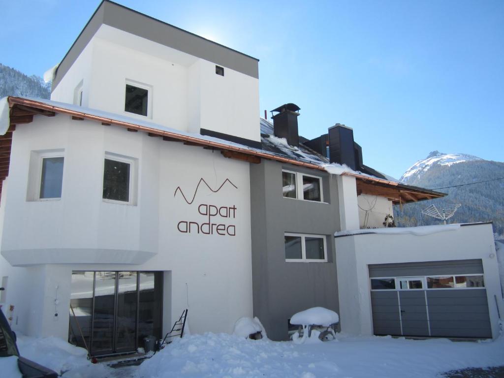 un edificio blanco con un cartel en la nieve en Apart Andrea en Ischgl
