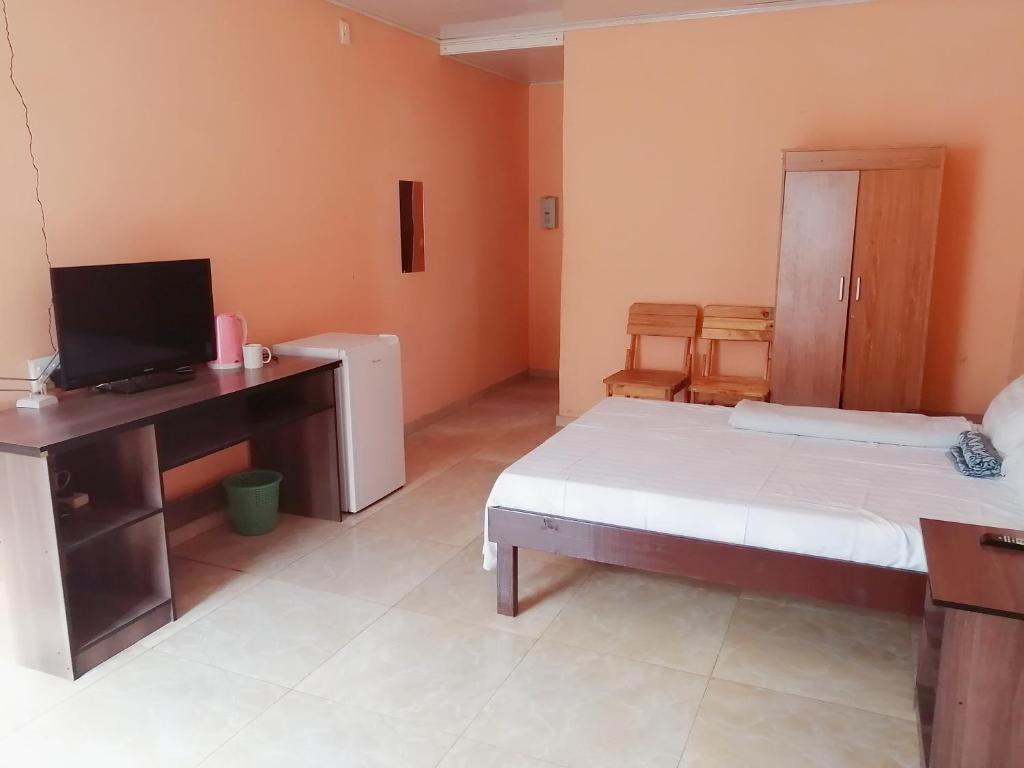 1 dormitorio con 1 cama y escritorio con TV en Prosperous Guest House, en Opuwo