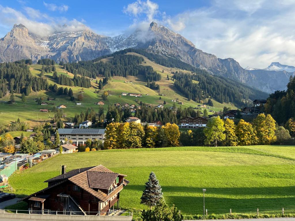 a house in a field with mountains in the background at 2-Zimmer Studio mit grossem Balkon und Bergpanorama - 400m von Talstation Sillerenbahn in Adelboden