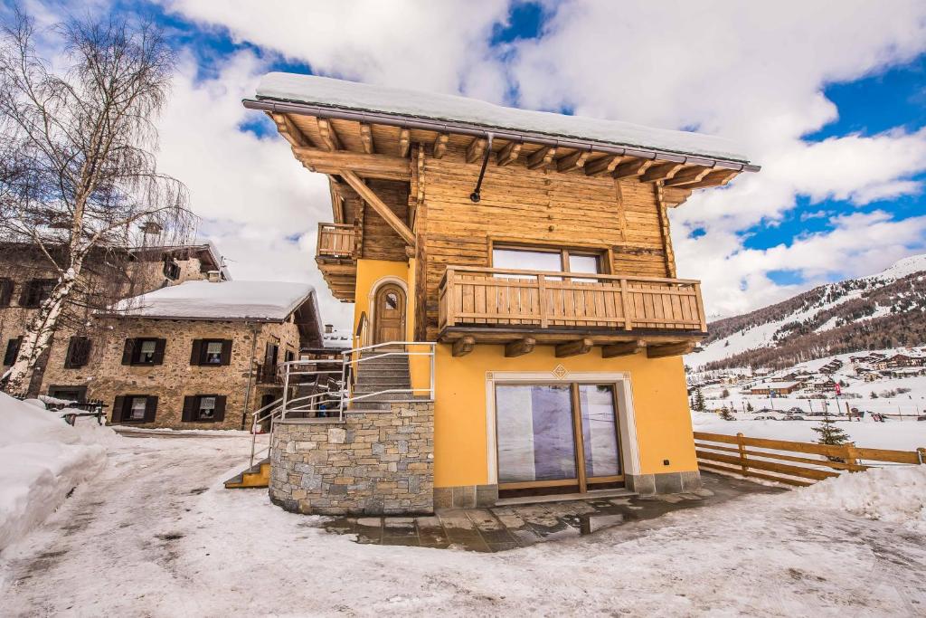 een houten huis met een balkon in de sneeuw bij Chalet 4 Stagioni in Livigno