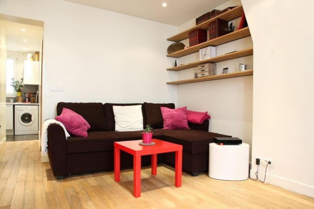 een woonkamer met een zwarte bank en een rode tafel bij JULES JO in Parijs