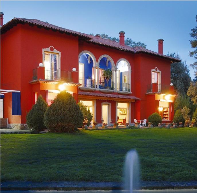 una casa roja con una fuente frente a ella en Hotel Torre Marti, en Sant Juliá de Vilatorta