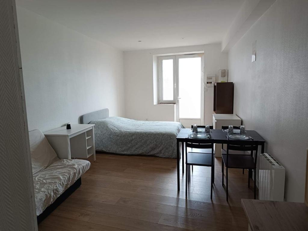 um pequeno quarto com uma mesa e uma cama em Jolie studio em Saint-Pourçain-sur-Sioule