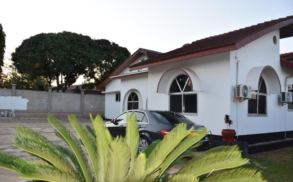 a car parked in front of a white house at La Casa Preciosa in Tanga