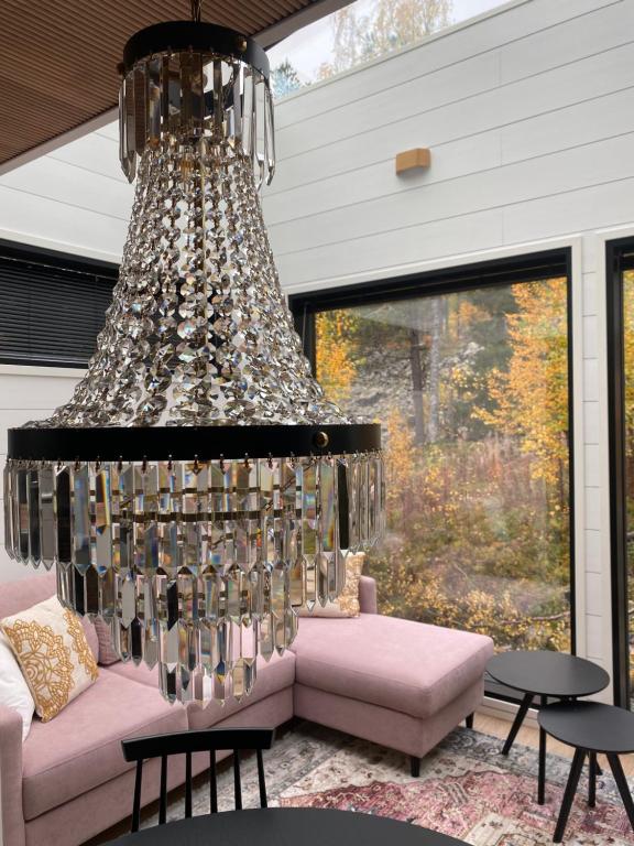 a large chandelier in a living room with a pink couch at Glass Ceiling Suite Kipinä in Sirkka