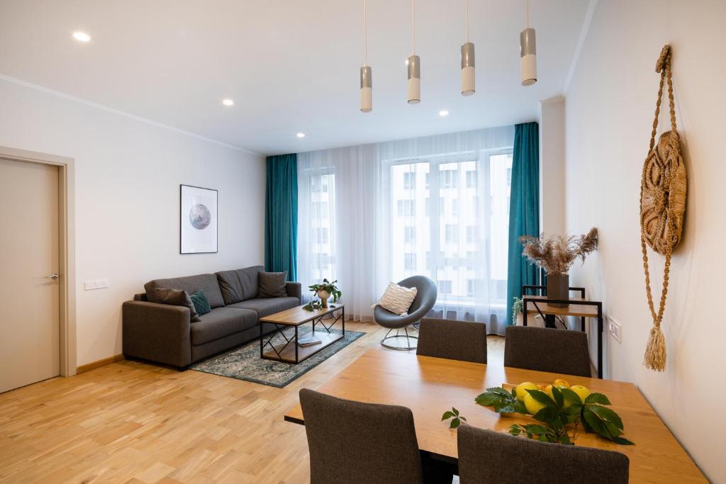 a living room with a table and a couch at Riverside Design Apartment with underground private parking in Rīga