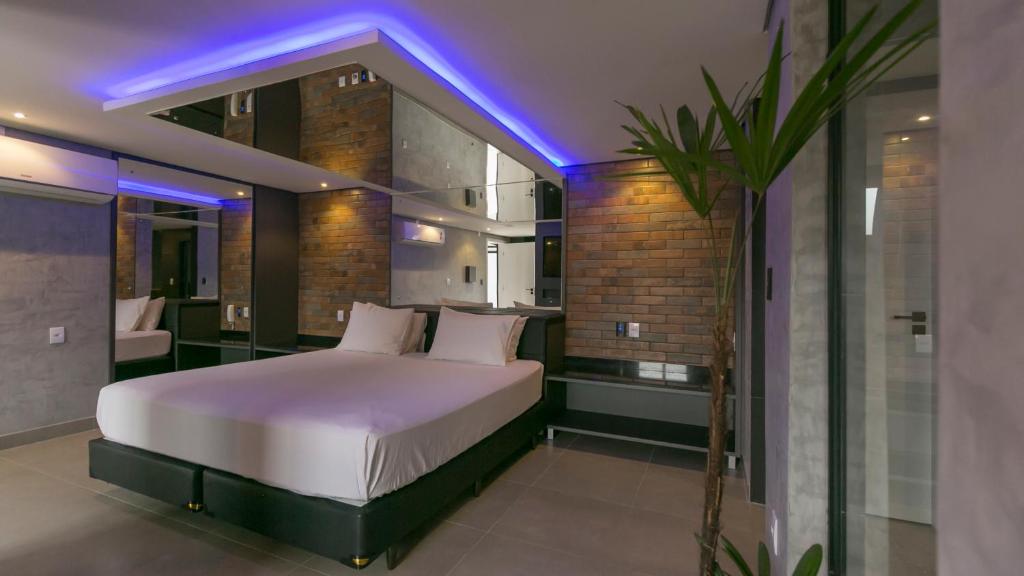 Dormitorio con cama con iluminación púrpura en Bangalô Motel by Drops en Santa Maria