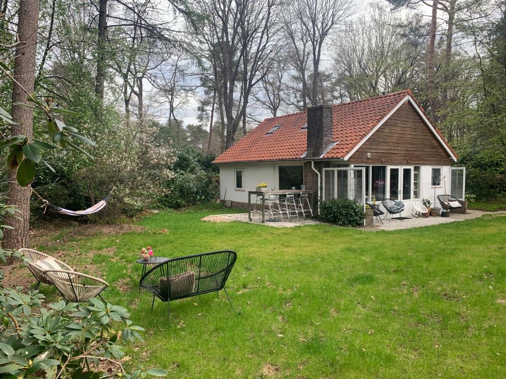 une petite maison blanche avec une table et des chaises dans une cour dans l'établissement Het Slakkenhuisje, à Maarn