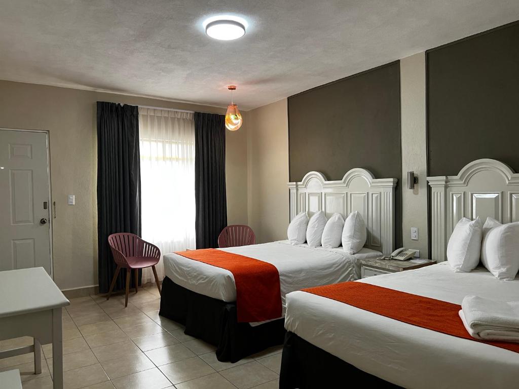 a hotel room with two beds and a table and chairs at HOTEL LOS ROBLES in Nuevo Laredo
