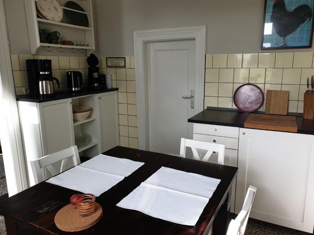 a kitchen with a table with white cabinets and a counter top at Ferienwohnung Medemgarten in Neuenkirchen