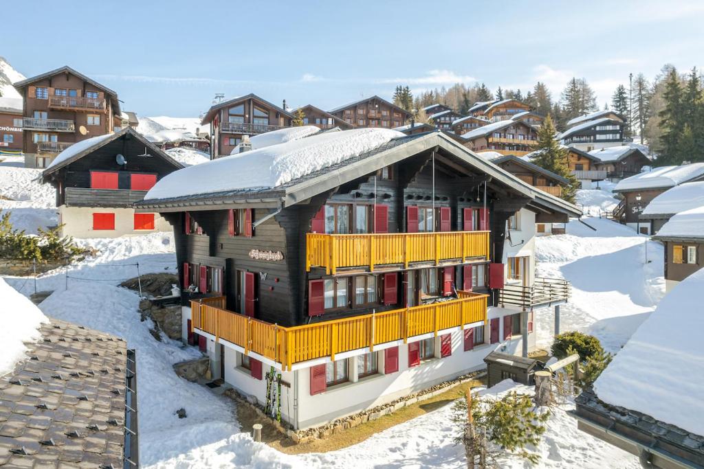 ein Gebäude mit einem schneebedeckten Dach auf schneebedeckten Häusern in der Unterkunft Schwarzbueb in Bettmeralp