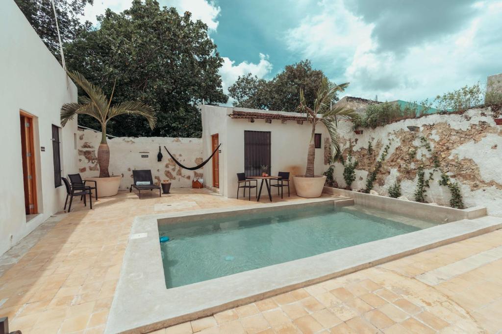 een zwembad in een patio met stoelen en een muur bij Hotel Casa Piedad in Campeche