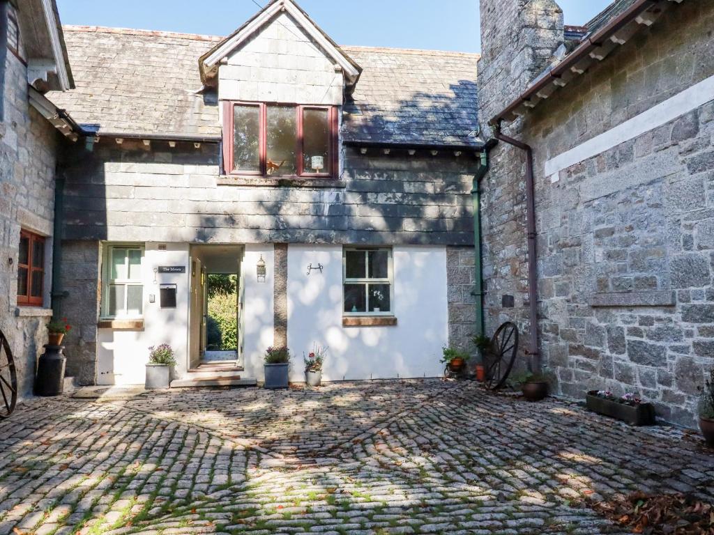 an old stone house with a brick driveway at The Mews in Bodmin