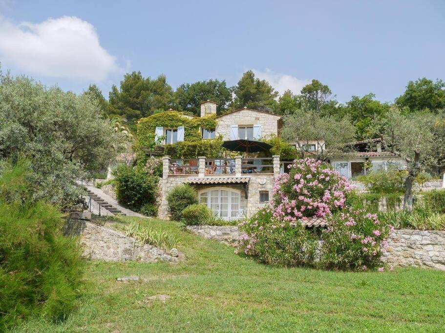 une grande maison en pierre sur une colline fleurie dans l'établissement L'Olivette - Mas Provencal, Panoramic View & Pool, à Callian