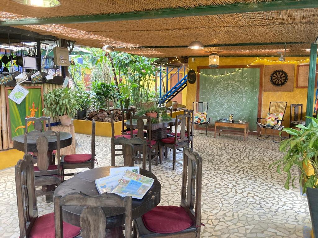 una sala da pranzo con tavoli, sedie e lavagna di Montaña Linda Hostel Orosi a Orosí