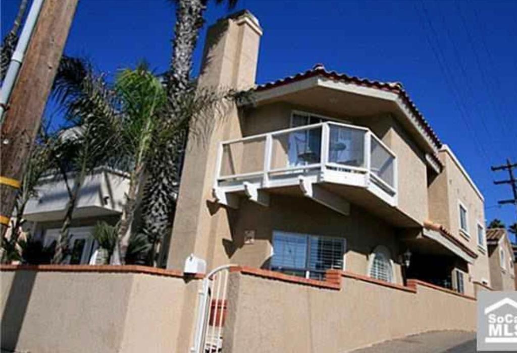 a house with a balcony on top of it at Pacific Breeze Right Next to Huntington Beach Pier! Steps from Beach!! in Huntington Beach