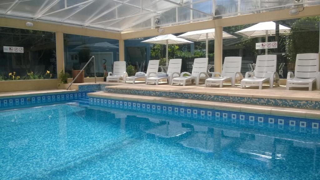 una piscina con sillas blancas y una piscina en Casa Celeste en Valeria del Mar