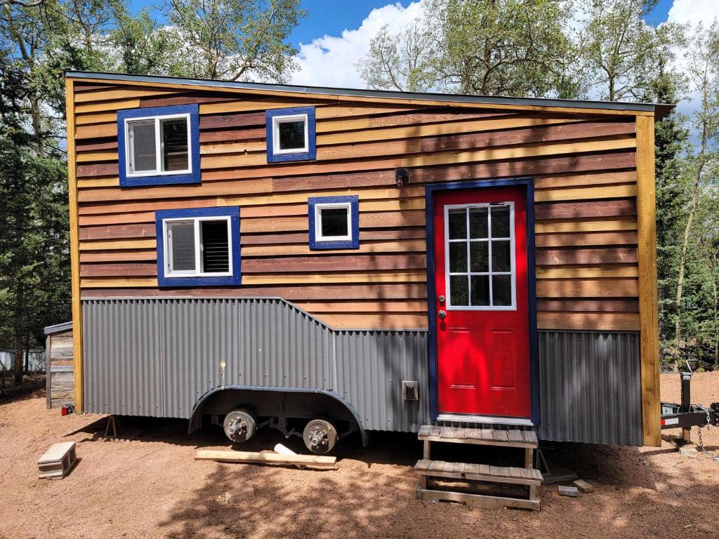 a tiny house with a red door and windows at NEW Lovable Mountain Tiny Home near Cripple Creek in Cripple Creek