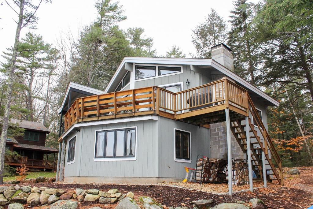 a house with a deck on the side of it at Tree Top Getaway in Laconia